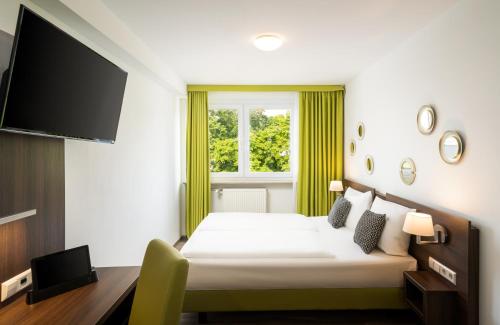 a hotel room with a bed and a flat screen tv at Arthotel ANA Eden in Karlsruhe