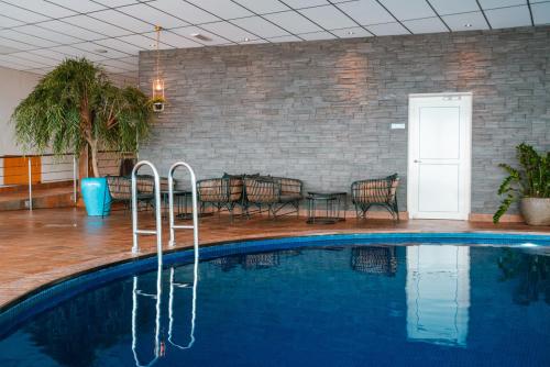 a pool in a room with a table and chairs at Hotell Hallstaberget in Sollefteå