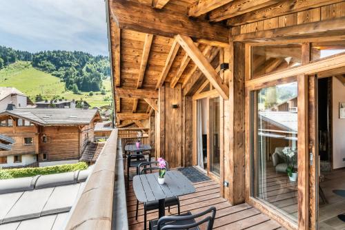 Casa de madera con balcón con mesa y sillas en Apartment Lizay Morzine - by EMERALD STAY, en Morzine