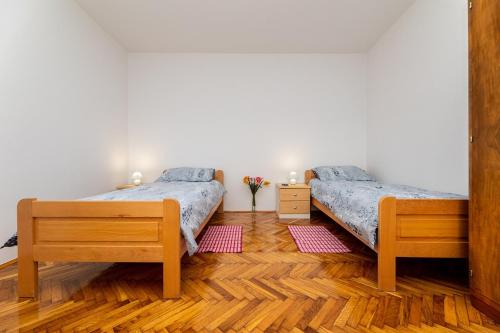 dwa łóżka w pokoju z drewnianą podłogą w obiekcie Apartment Josip Brusic w mieście Gabonjin