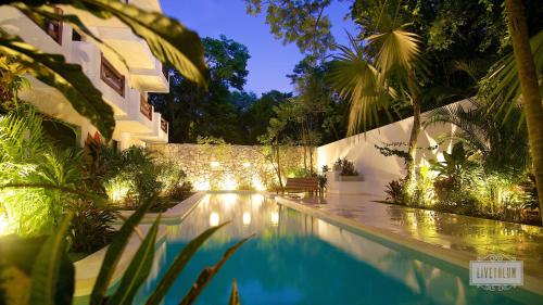 a swimming pool with lights in a backyard at night at LiveTulum in Tulum