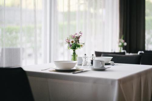 a table with two cups and a vase of flowers on it at Hotel Fronza - your hike & mountain home in Lutago