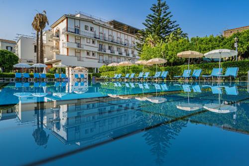 a hotel swimming pool with chairs and umbrellas at Aequa Hotel in Vico Equense