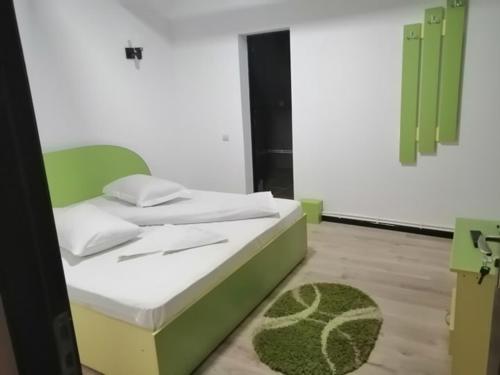 Schlafzimmer mit einem Bett mit einem grünen Kopfteil in der Unterkunft Pensiunea Denisa in Săcăluşeşti