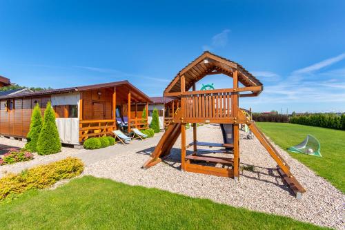 une aire de jeux en bois avec toboggan et une maison dans l'établissement Domki 3W Wicie, à Wicie