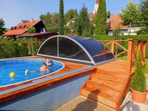 dos personas en una piscina con cubierta en una terraza en Greenhouse, en Teplý Vrch
