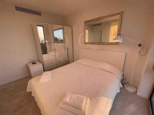 a bedroom with a white bed and a mirror at PINEA Apartments Pobierowo z niesamowitym widokiem na morze oraz jacuzzi w wybranych apartamentach in Pobierowo