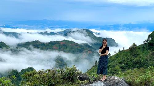 a woman standing on top of a mountain with clouds at Nobita Homestay bắc hà in Bắc Hà