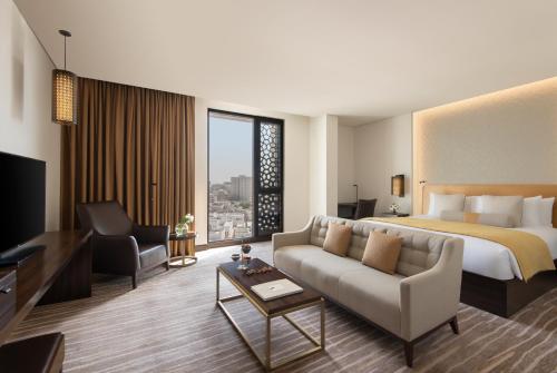 a hotel room with a bed and a couch at Alwadi Hotel Doha - MGallery Collection in Doha