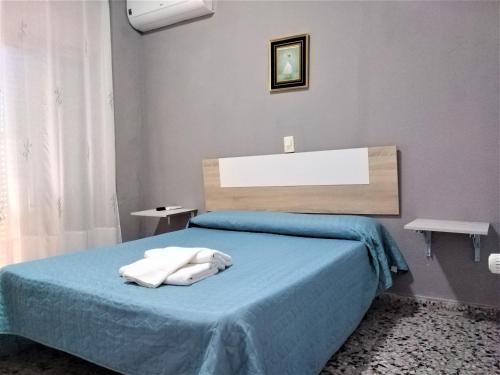 una camera da letto con un letto blu con due asciugamani di Habitaciones de Hostal a Primera linea de playa en Cullera a Cullera
