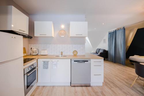 a kitchen with white appliances and a living room at Appartements Le Bleu des Roches Noires in Saint-Gilles les Bains