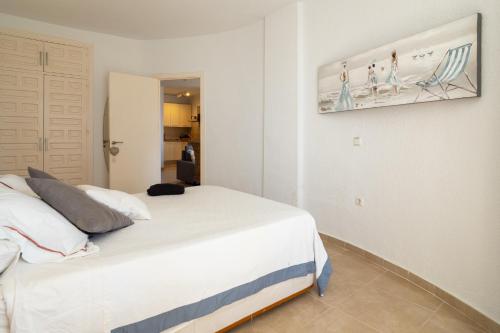 Un dormitorio con una cama blanca y una pintura en la pared en MD001 Precioso Apartamento en Primera Linea de Playa, en Mijas Costa