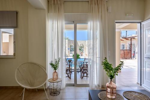 een woonkamer met glazen schuifdeuren en een tafel met stoelen bij Azure Beach Villas in Kissamos