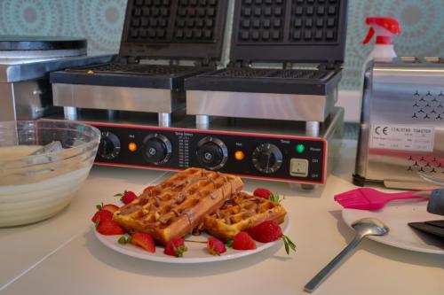 a plate of waffles and strawberries on a counter at Alexis Hotel in Chania Town