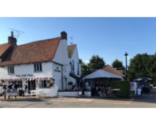 un gran edificio blanco con una tienda delante de él en The Yew Tree, en Manuden