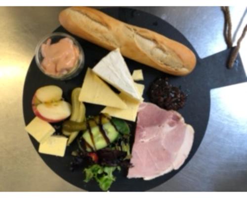 a black plate of food with cheese and other foods at The Yew Tree in Manuden