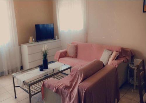 ein Wohnzimmer mit einem rosa Sofa und einem TV in der Unterkunft Blue Appartment in Nea Iraklitsa