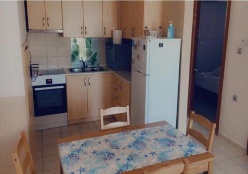 uma cozinha com uma mesa e um frigorífico branco em Blue Appartment em Iraklitsa