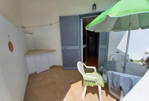 a kitchen with a table with a green umbrella at Meerblick-Ferienhaus Casa Gino Apulien in San Pietro in Bevagna