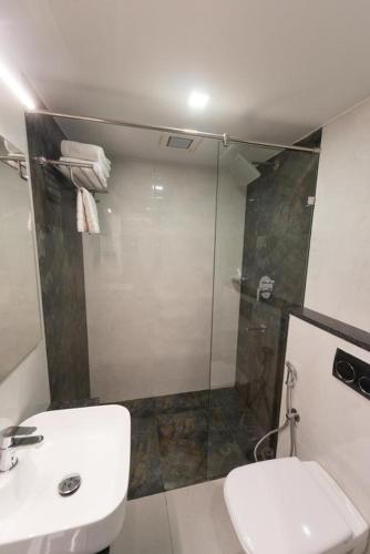 a bathroom with a shower and a toilet and a sink at Hotel Vijay Fablis in Coimbatore