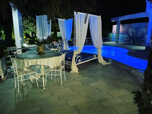 a table and chairs next to a pool at night at Fruška Gora Klub Krstašice in Irig