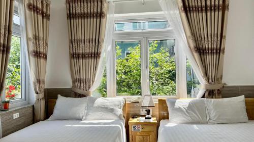 two beds in a room with two windows at Villa - Hotel Nam Khang 2 Dalat in Da Lat