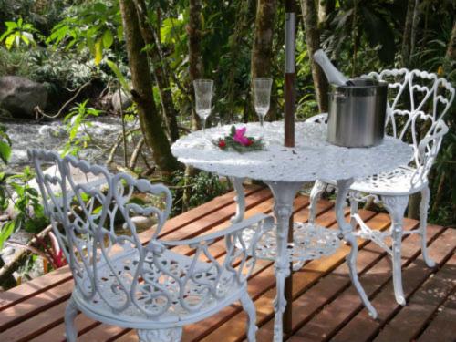 einen Tisch und zwei Stühle auf einer Holzterrasse in der Unterkunft Pousada Chalés Canto do Rio in Visconde De Maua