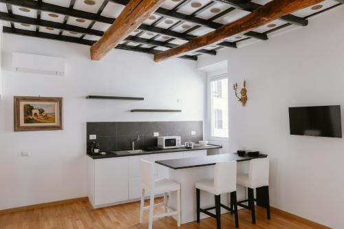 eine Küche mit weißen Wänden und einem Tisch mit weißen Stühlen in der Unterkunft Charming Frattina - 2 bathrooms new apartment in Rom
