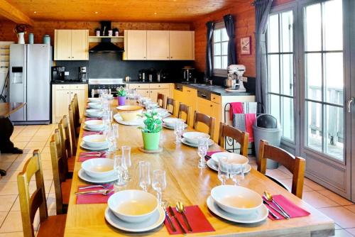 une longue table dans une cuisine avec des assiettes et des verres dans l'établissement Chalet Hestia - CHALET 4 - 16 PERSONNES 280M² MAE-9284, au Corbier