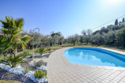 einen Pool in einem Garten mit Bäumen und Sträuchern in der Unterkunft Villa Oleander in Manerba del Garda