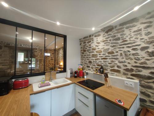 a kitchen with a stone wall and a sink at Appart Halo et Duplex Les Filles in Dinan