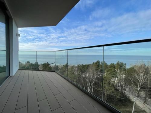 a balcony with a view of the ocean and trees at PINEA Apartments Pobierowo z niesamowitym widokiem na morze oraz jacuzzi w wybranych apartamentach in Pobierowo
