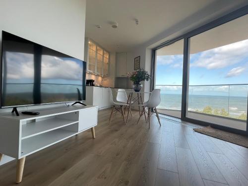 a living room with a white desk and large windows at PINEA Apartments Pobierowo z niesamowitym widokiem na morze oraz jacuzzi w wybranych apartamentach in Pobierowo
