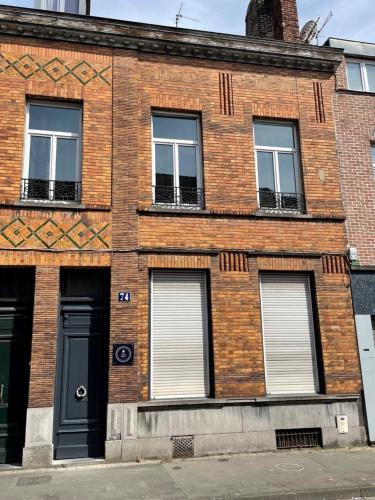 un edificio de ladrillo con una puerta y ventanas negras en NG SuiteHome - Lille I Roubaix Centre I Collège - Balnéo - Netflix - Wifi, en Roubaix