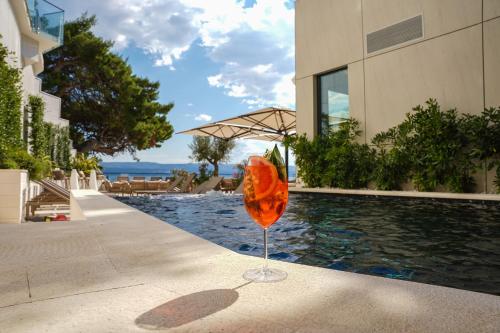 an orange glass sitting next to a swimming pool at Hotel Medistone in Omiš