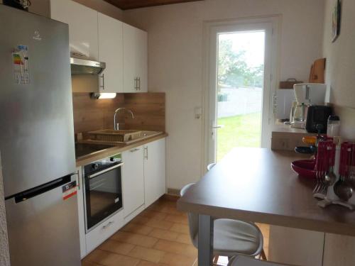 une cuisine avec un réfrigérateur en acier inoxydable et une table dans l'établissement Maison plain pied tout confort, proche plage, 6 couchages, terrasse, 2 chambres, parking, Wi-Fi optionnel - FR-1-224A-383, à Bretignolles-sur-Mer