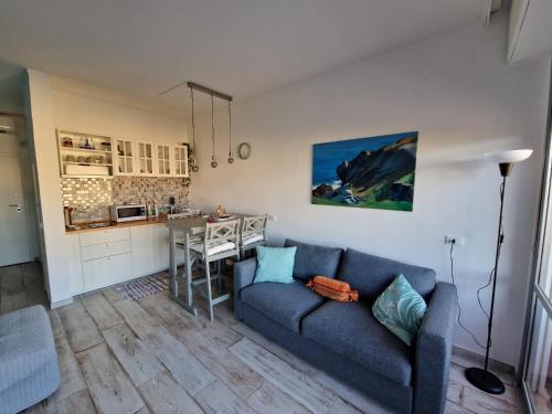 een woonkamer met een blauwe bank en een keuken bij Casa Marina - Monolocale vista mare in Follonica