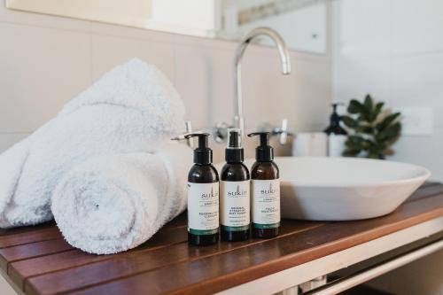 three bottles of wine sitting on a counter next to a sink at S T U D I O 22 Peaceful Retreat with Garden Views in Port Lincoln