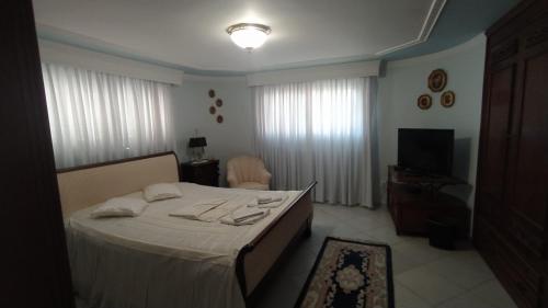 una camera da letto con un letto con lenzuola bianche e una TV di Villa Luxury a Kavala