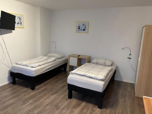 a room with two beds and a tv in it at Bed4You Gästehaus 1 in Bergshausen