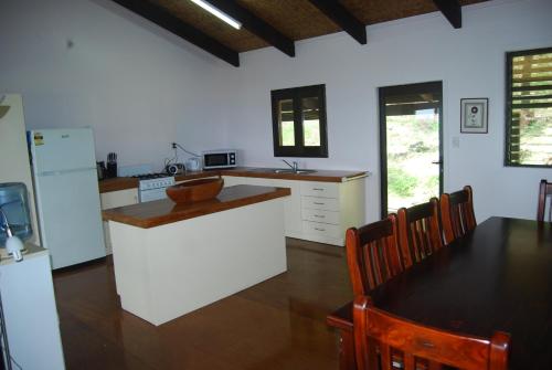 a kitchen with a table and a kitchen with white appliances at Moana Villa Aitutaki in Arutanga