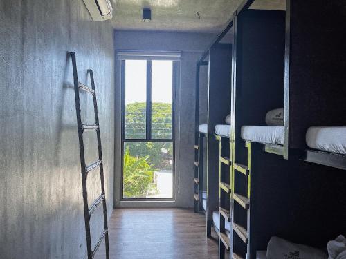 a room with a hallway with bunk beds and a window at Shorebreak Hostel San Juan La Union in san juan la union