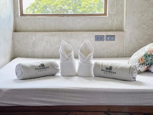 a pair of white shoes and pillows on a bed at Shorebreak Hostel San Juan La Union in san juan la union