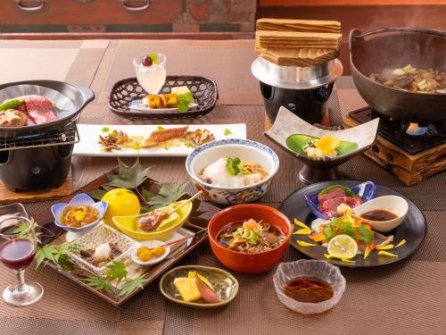 einen Tisch mit Teller mit Lebensmitteln und Schüsseln mit Lebensmitteln in der Unterkunft Yunohara in Mogami