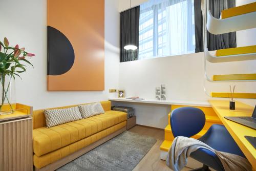 a living room with a yellow couch and a desk at Citadines Connect City Centre Singapore in Singapore