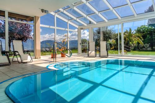 una piscina cubierta con techo de cristal y una piscina en DAS MATSCHER Residence & Garden Hotel, en Appiano sulla Strada del Vino
