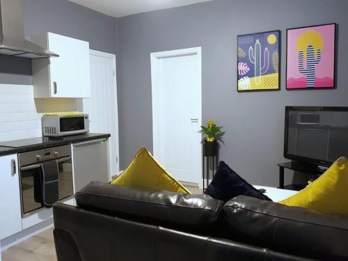 The Westside with Parking في يورك: غرفة معيشة مع أريكة جلدية ووسائد صفراء