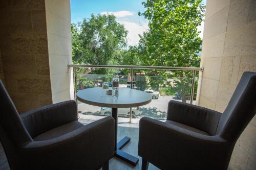a patio with a table and two chairs and a window at B Hotel Bishkek in Bishkek