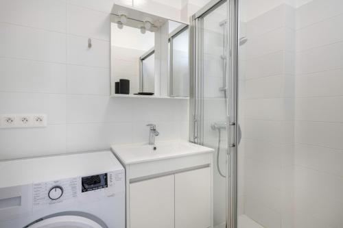 uma casa de banho branca com um lavatório e uma máquina de lavar roupa em Bienvenue a Pornichet dans cet appartement vue mer em Pornichet