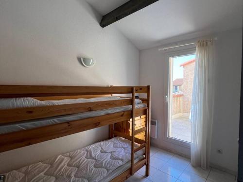 une chambre avec deux lits superposés et une fenêtre dans l'établissement Villa T3 en bord de mer avec piscine, 6 personnes - Le Barcarès - FR-1-81-494, au Barcarès